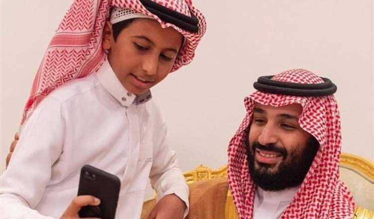 طفل يتكئ على كتف "ولي العهد" ويلتقط صورة سيلفي